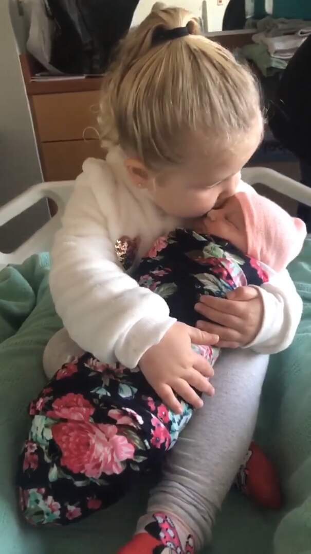 Bambina di 3 anni tiene in braccio la sorellina neonata per la prima volta,  ed è